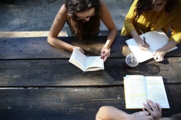 People studying books at a picnic table.