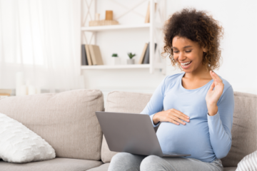 pregnant woman using laptop smiling and waving to screen